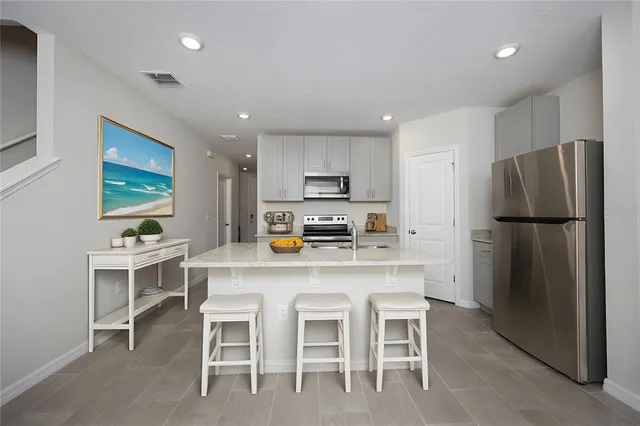 a kitchen with stainless steel appliances a refrigerator a stove a dining table and chairs