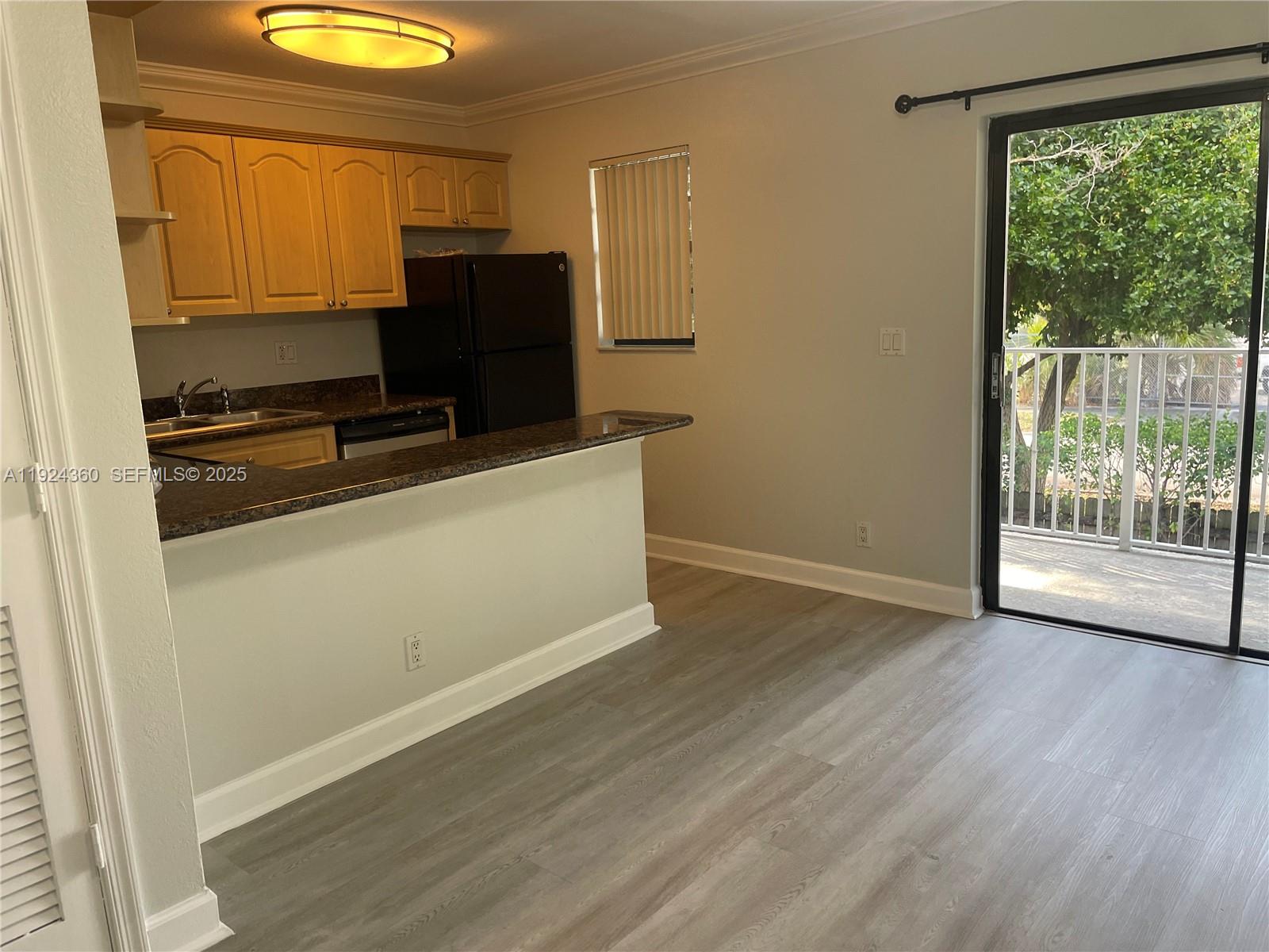 1401 Northeast 53rd Street, Unit 211 Fort Lauderdale, FL 33334 - Photo 2 of 14 a kitchen with wooden cabinets and a refrigerator