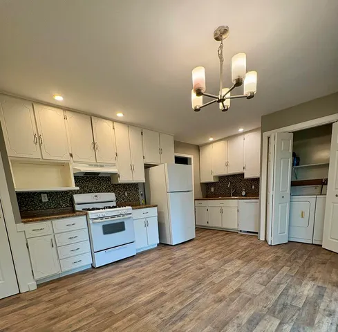 a kitchen with granite countertop a stove cabinets and wooden floor