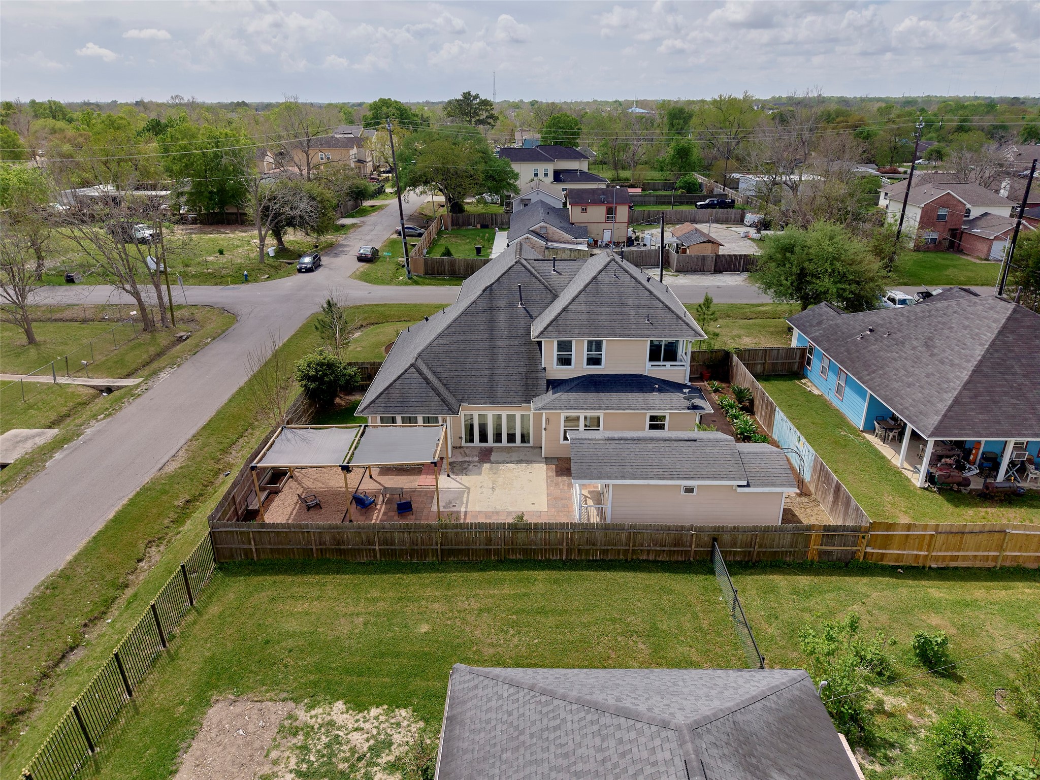 4219 Redbud Street Houston, TX 77051 - Photo 24 of 25 This aerial view showcases a spacious two-story home with a large fenced backyard, a covered patio area, and a separate structure, ideal for outdoor living. Located in a quiet neighborhood, the property is bordered by well-kept homes and lush greenery, providing a serene setting.