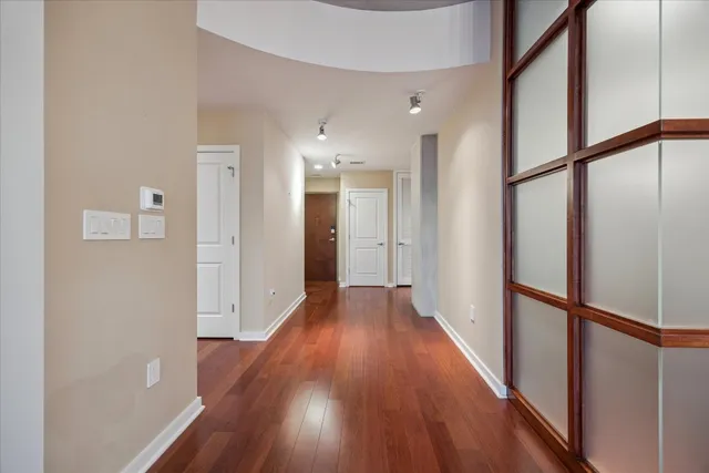 a view of a hallway with wooden floor and a living room