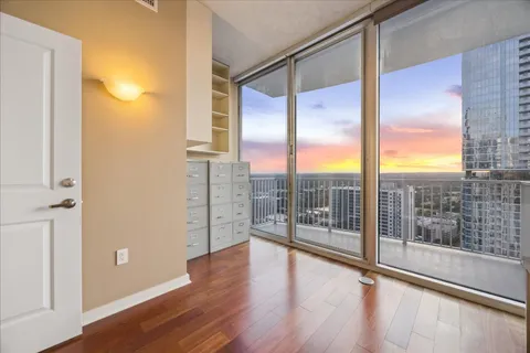 a view of an empty room with wooden floor and windows