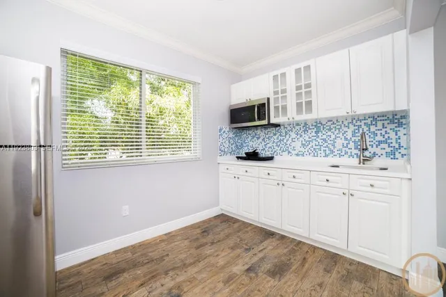 a kitchen with granite countertop white cabinets and a window