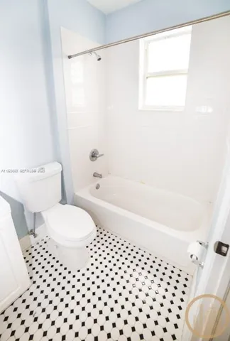 a bathroom with a toilet a window and a bathtub