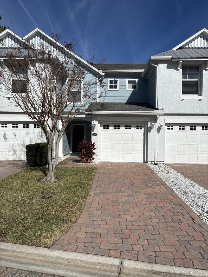 Traditional home with decorative driveway, an attached garage, and a front yard