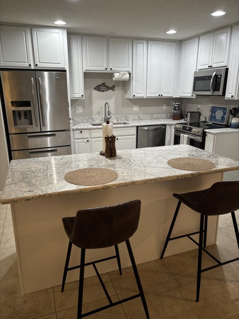 109 Islander Drive St. Augustine, FL 32080 - Photo 3 of 6 Kitchen featuring a kitchen breakfast bar, white cabinets, appliances with stainless steel finishes, and recessed lighting