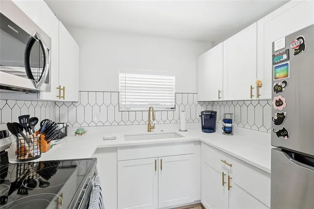 a kitchen with stainless steel appliances a sink a stove and white cabinets