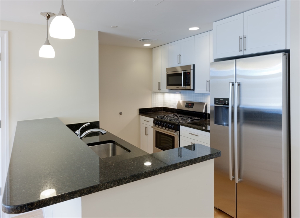 a kitchen with stainless steel appliances granite countertop a sink a stove and a refrigerator