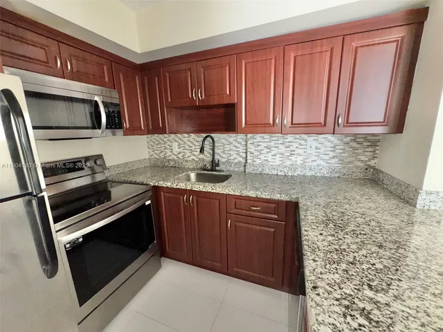 a kitchen with granite countertop a stove microwave and sink
