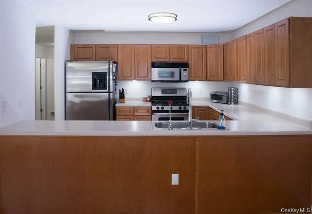 a kitchen with kitchen island a counter top space a sink and stainless steel appliances