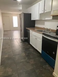 a kitchen with granite countertop a stove a sink and a refrigerator