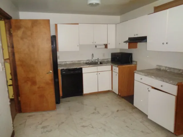 a kitchen with stainless steel appliances granite countertop a refrigerator a stove a sink and white cabinets