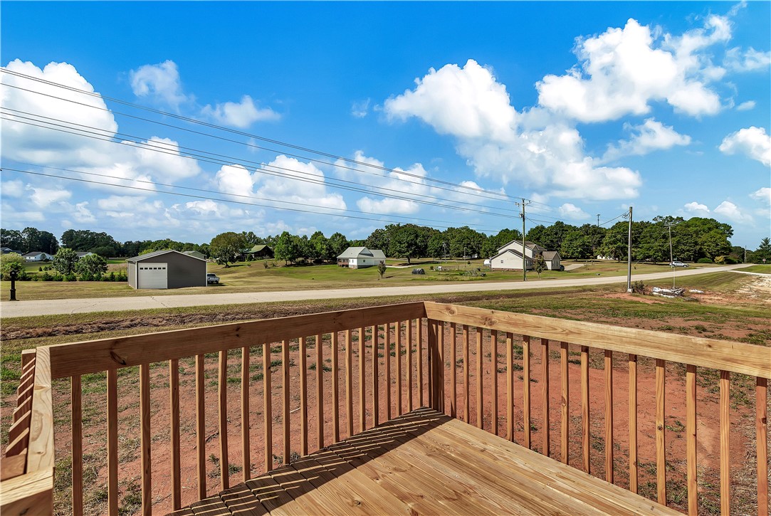 205 Wade Farm Road Fair Play, SC 29643 - Photo 8 of 23 An elevated wooden deck overlooks peaceful neighborhood surroundings under a wide blue sky.