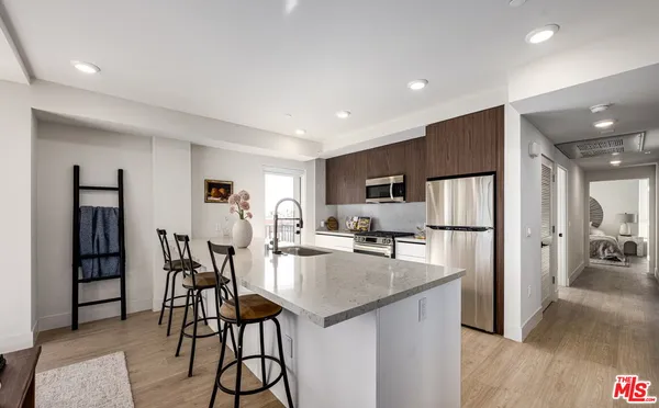 a kitchen with stainless steel appliances kitchen island granite countertop a refrigerator a stove and a dining table with wooden floor