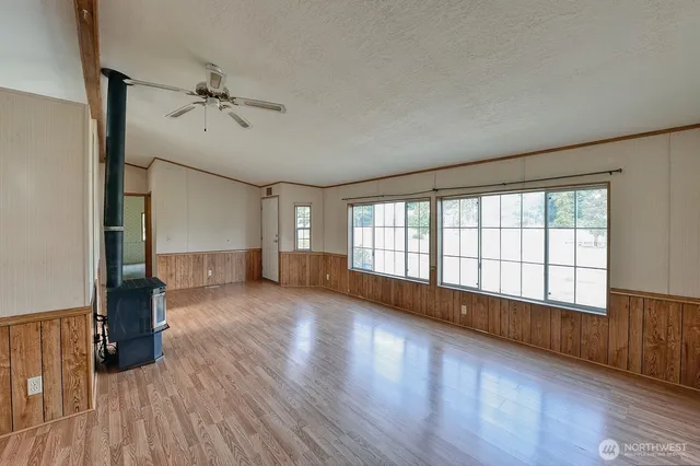 a view of an empty room with a window and wooden floor