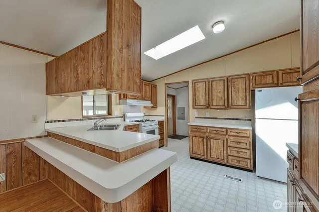 a kitchen with stainless steel appliances granite countertop a refrigerator a stove and a sink with cabinets