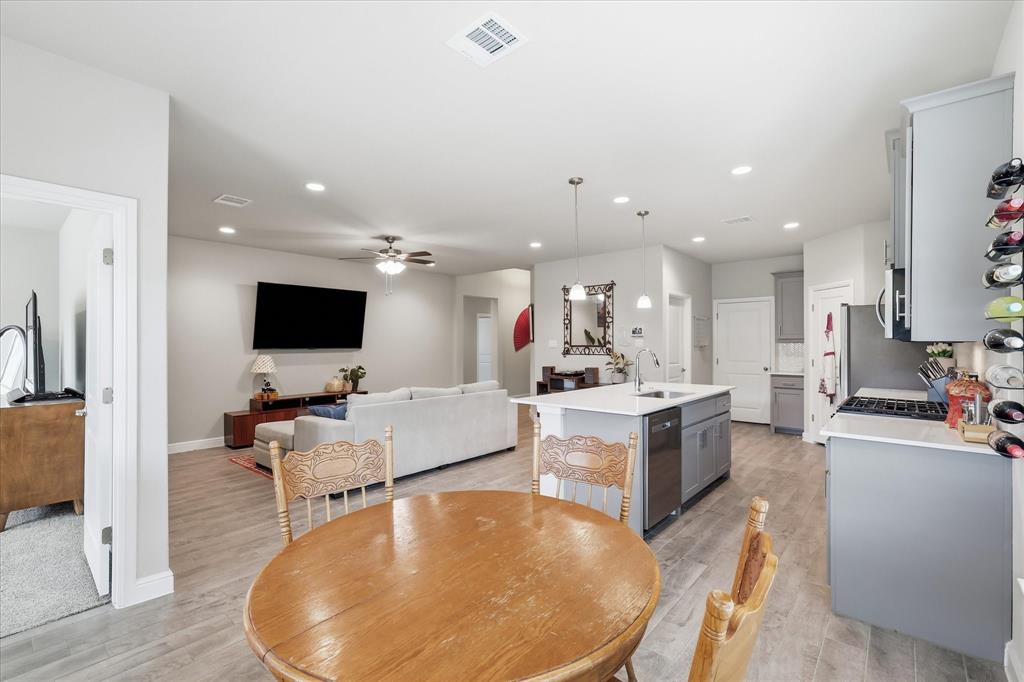 141 Medina Lane Rhome, TX 76078 - Photo 12 of 36 Open-concept living space featuring wood-finish flooring, recessed lighting, a ceiling fan, a kitchen island with seating, and light gray cabinetry