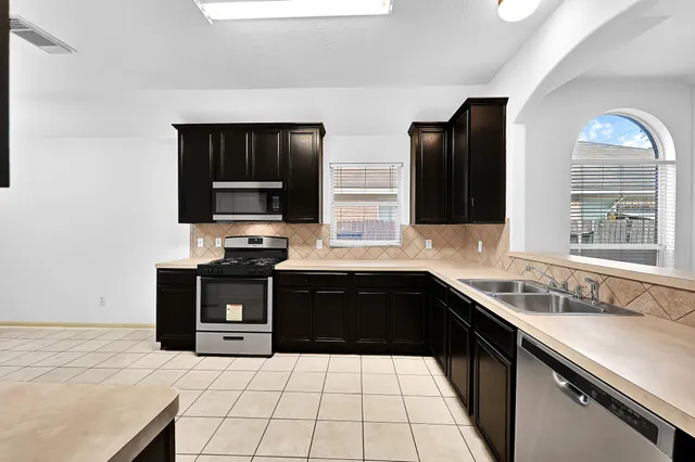 a kitchen with stainless steel appliances a sink dishwasher stove and refrigerator