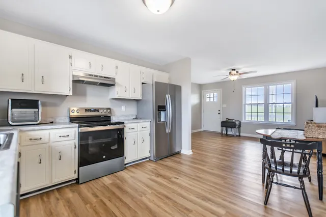 a kitchen with stainless steel appliances granite countertop a stove a refrigerator a kitchen island a stove and a wooden floors