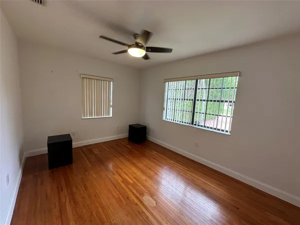 a view of an empty room with a window and wooden floor