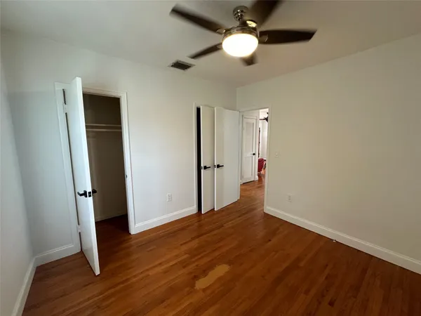 an empty room with wooden floor and a ceiling fan