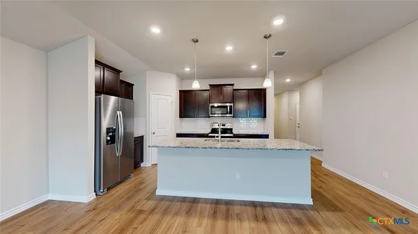 a kitchen with stainless steel appliances granite countertop a sink stove and refrigerator