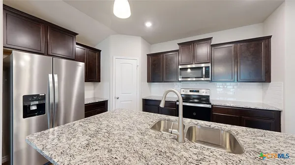 a kitchen with kitchen island granite countertop a sink and refrigerator