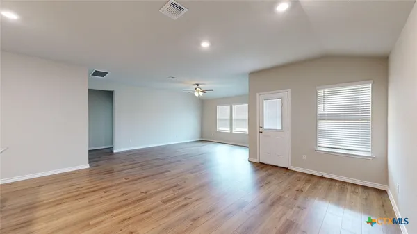 a view of an empty room with wooden floor and a window