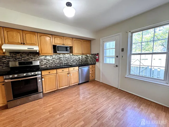a kitchen with granite countertop wooden floors and stainless steel appliances