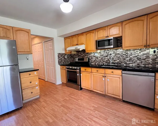 a kitchen with stainless steel appliances granite countertop a stove a sink and a refrigerator