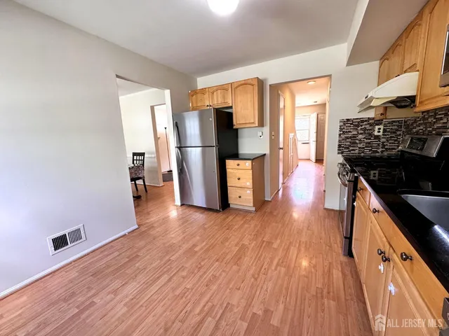a kitchen with stainless steel appliances a refrigerator and wooden floor
