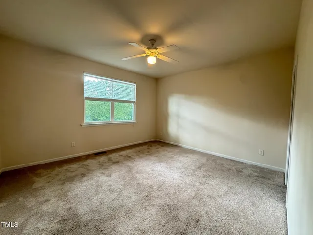 an empty room with a window and a fan