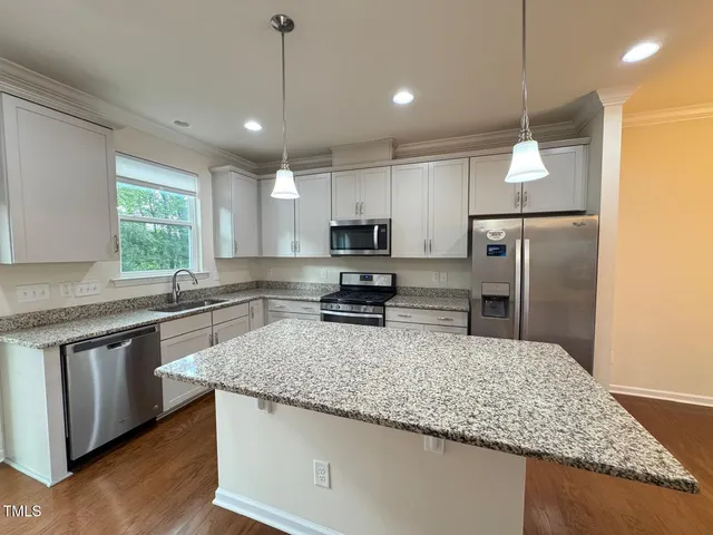 a kitchen with stainless steel appliances granite countertop a sink refrigerator and microwave