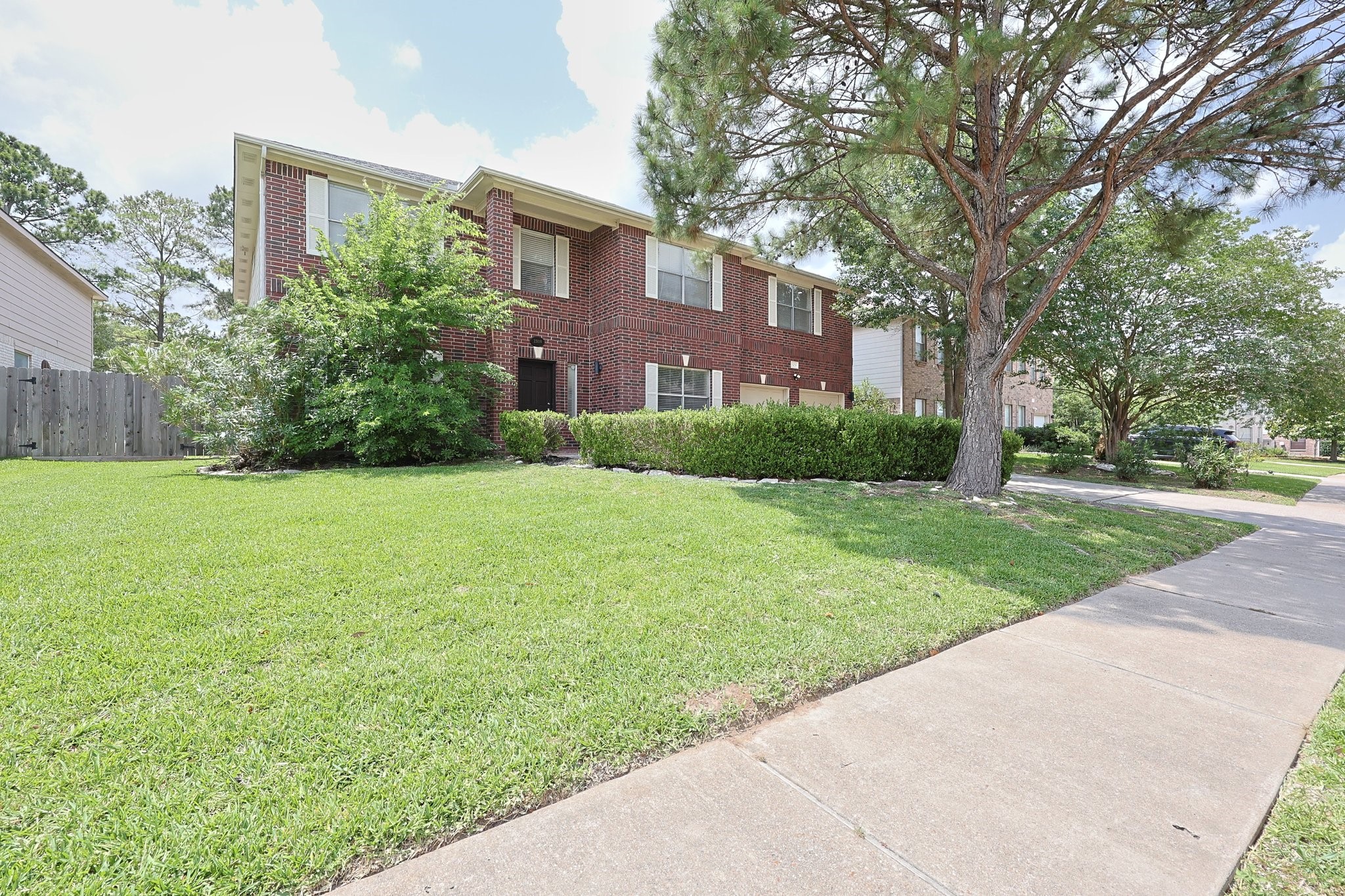 23019 Eastgate Village Drive Spring, TX 77373 - Photo 45 of 46 Charming two-story brick house with well-maintained landscaping, including lush green grass and mature trees. It features a spacious front yard and a welcoming sidewalk leading to the entrance.