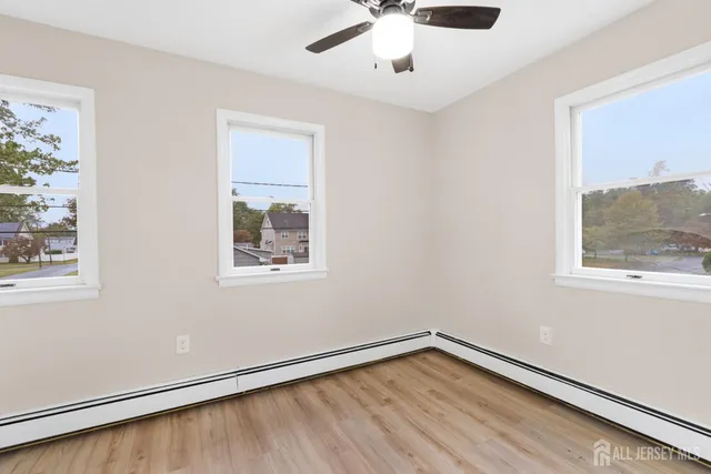 a view of an empty room with a window and wooden floor