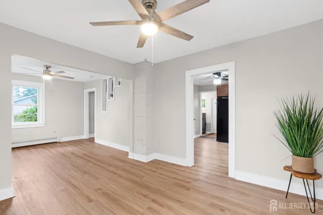 an empty room with wooden floor and a ceiling fan