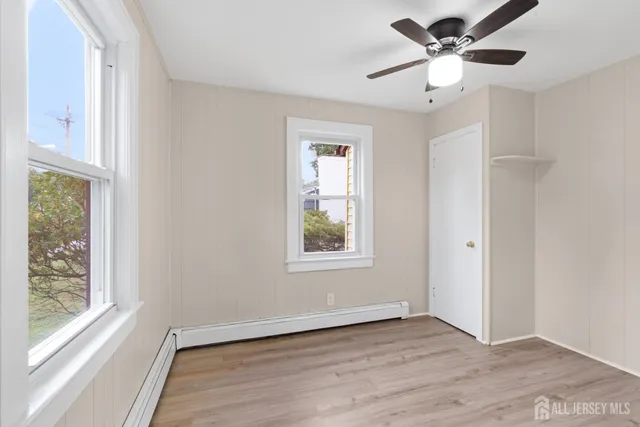 a view of an empty room with a window and wooden floor