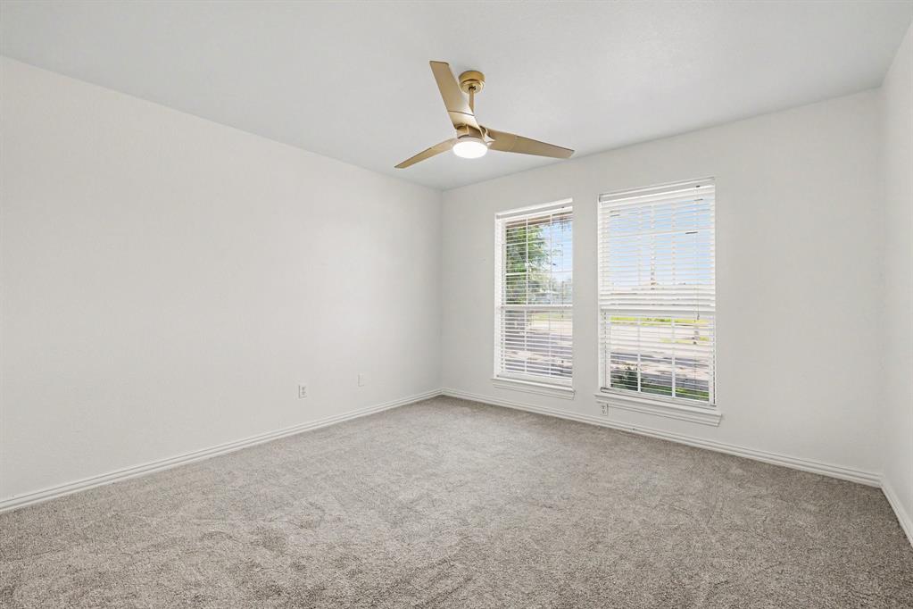 307 Dixon Street Terrell, TX 75160 - Photo 15 of 32 Neutral tone wall finishes, gray carpet flooring, two windows with blinds, white baseboards, and a contemporary ceiling fan with integrated lighting