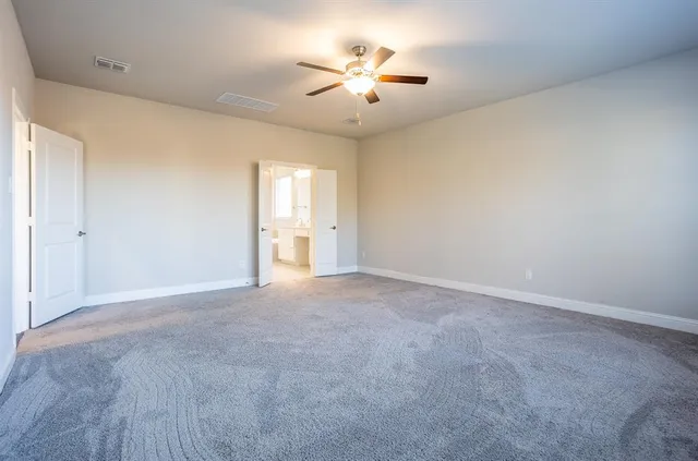 an empty room with chandelier fan and windows