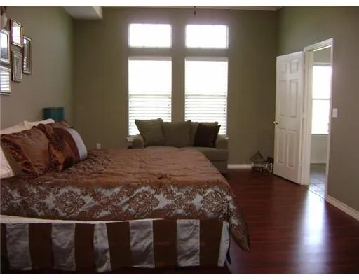 a bedroom with a bed window and wooden floor