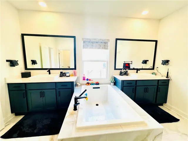 a large bathroom with a double vanity sink mirror and bathtub