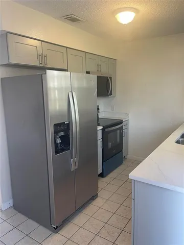 a kitchen with metallic refrigerator sink and cabinets