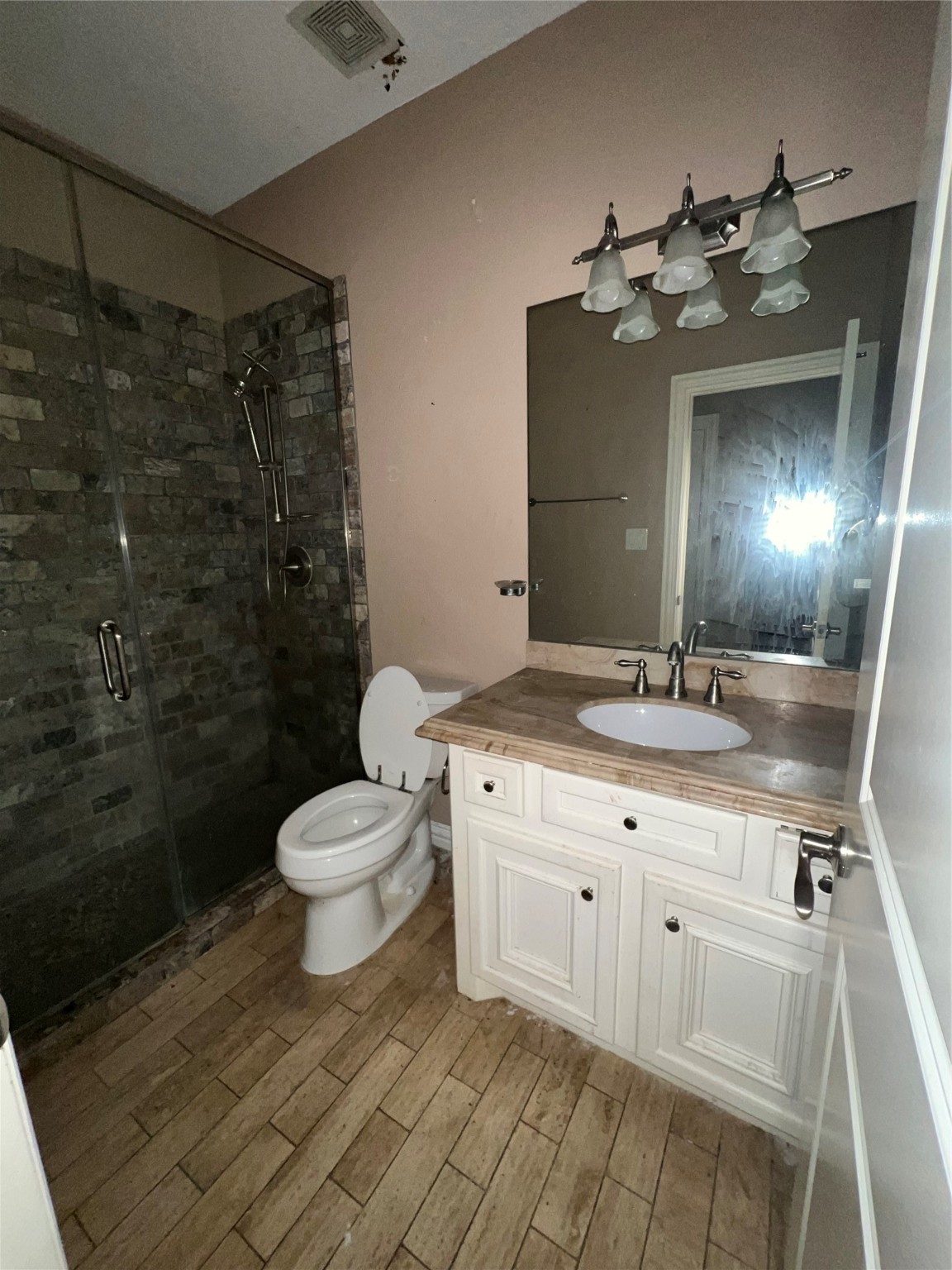 5771 Belarbor Street Houston, TX 77033 - Photo 5 of 6 a bathroom with a toilet a sink and mirror