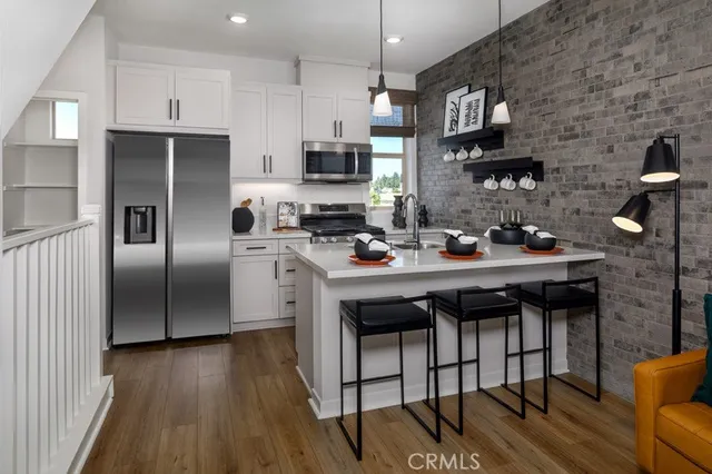 a kitchen with stainless steel appliances a refrigerator a stove a sink dishwasher and white cabinets with wooden floor