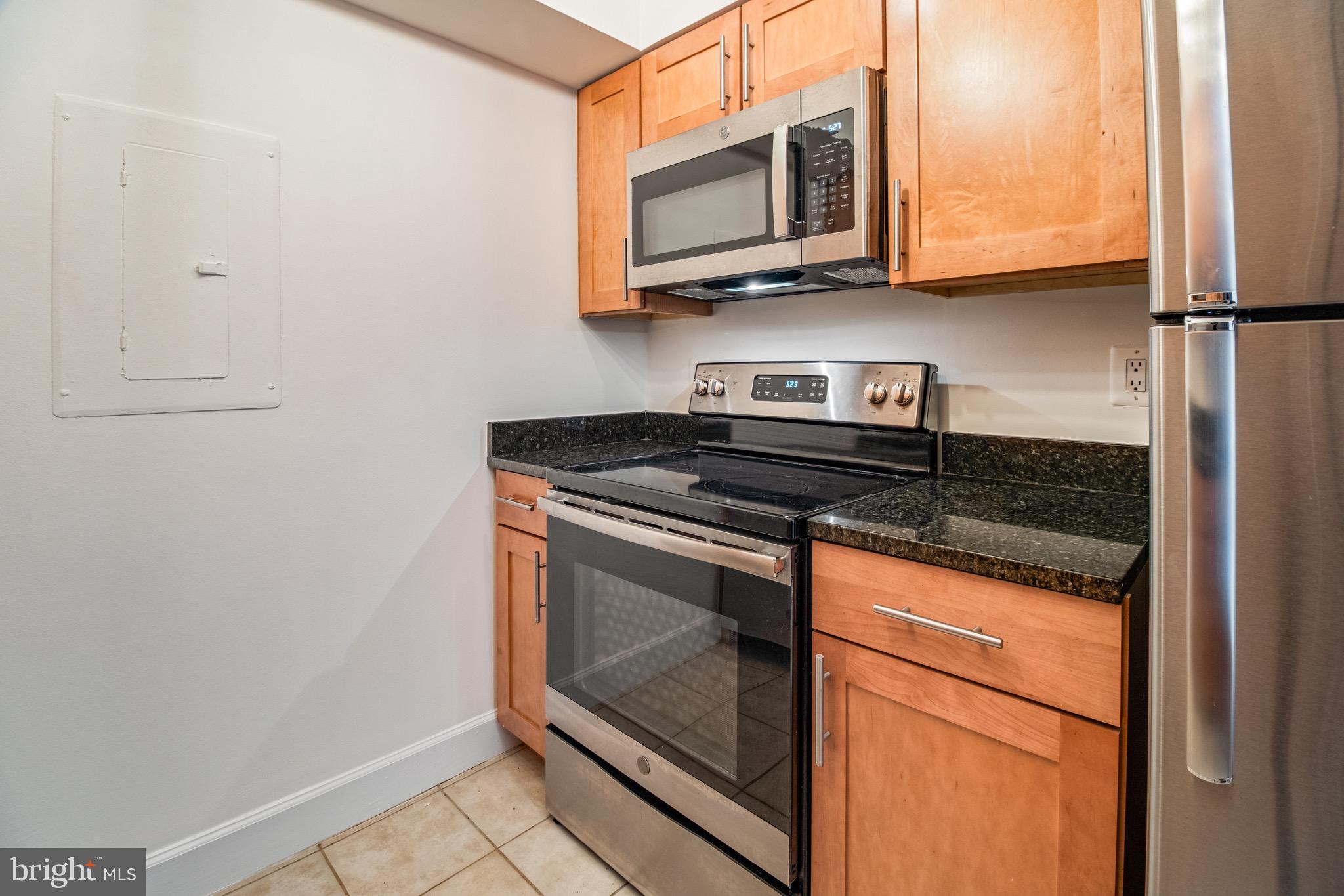 3401 38th Street Northwest, Unit 324 Washington, DC 20016 - Photo 8 of 23 a kitchen with stainless steel appliances granite countertop a stove a microwave and a refrigerator