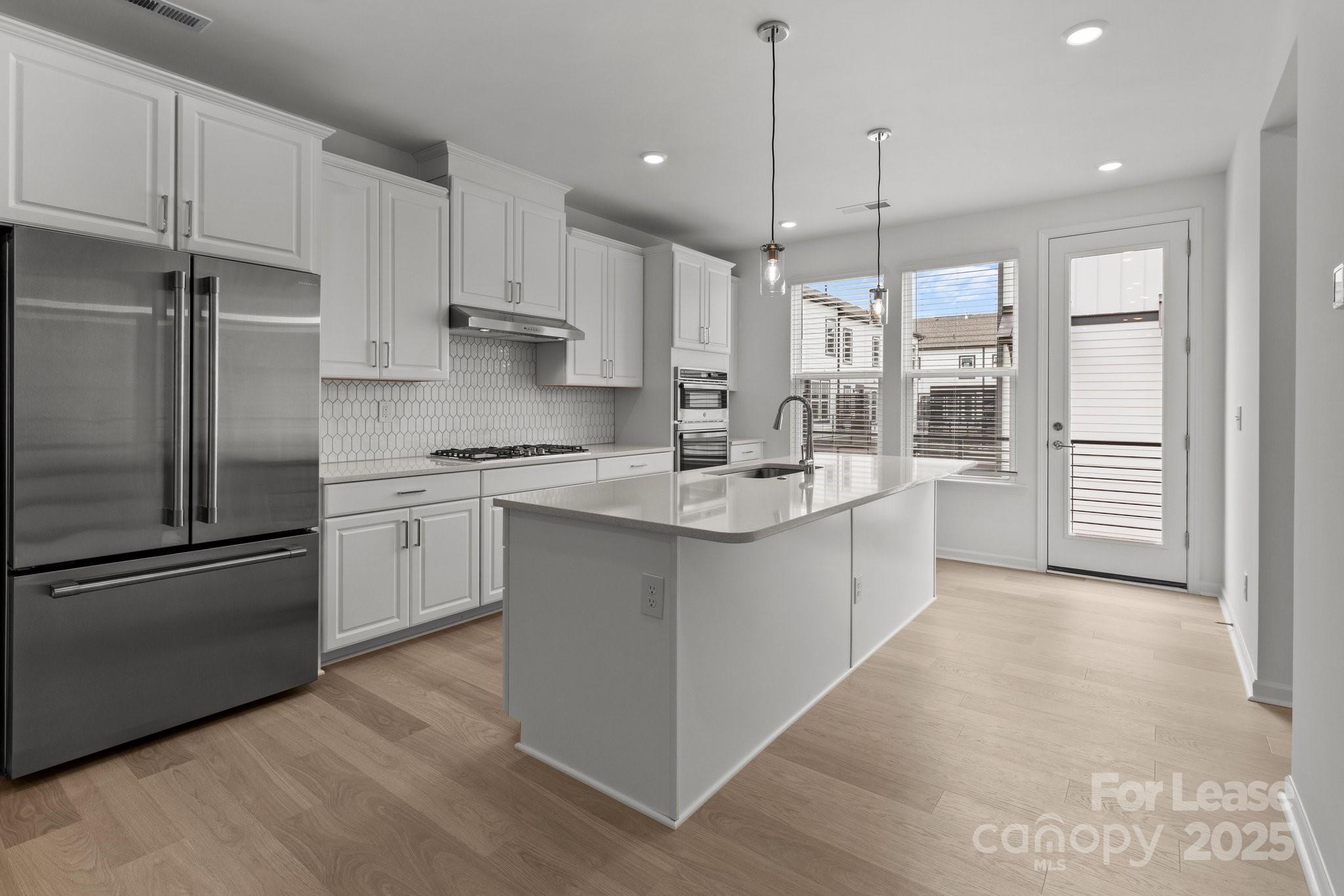 109 Goodson Place Davidson, NC 28036 - Photo 3 of 22 a kitchen with kitchen island white cabinets and stainless steel appliances