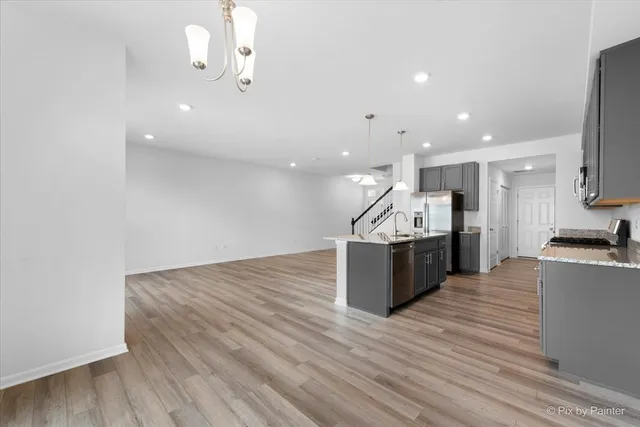 a kitchen with stainless steel appliances kitchen island wooden floors granite counter tops and a view of living room