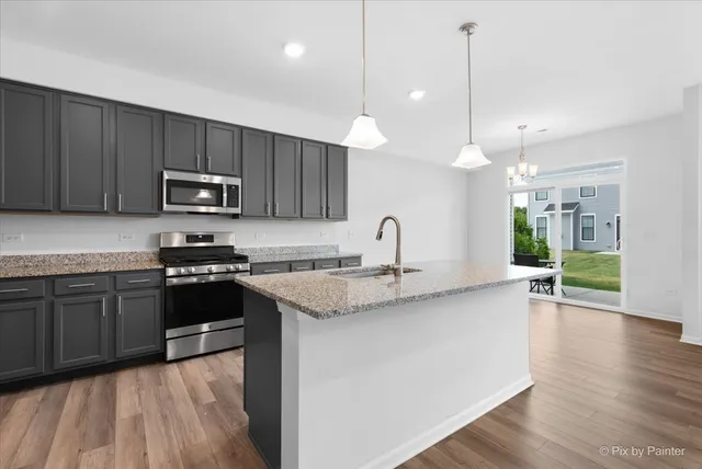 a kitchen with stainless steel appliances granite countertop a sink a stove and a wooden floors