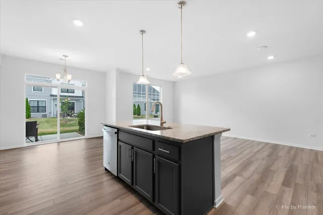 a kitchen with stainless steel appliances granite countertop a stove a sink a center island and a wooden floor