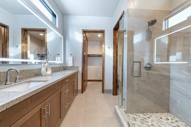 a spacious bathroom with a double vanity sink a mirror and a shower
